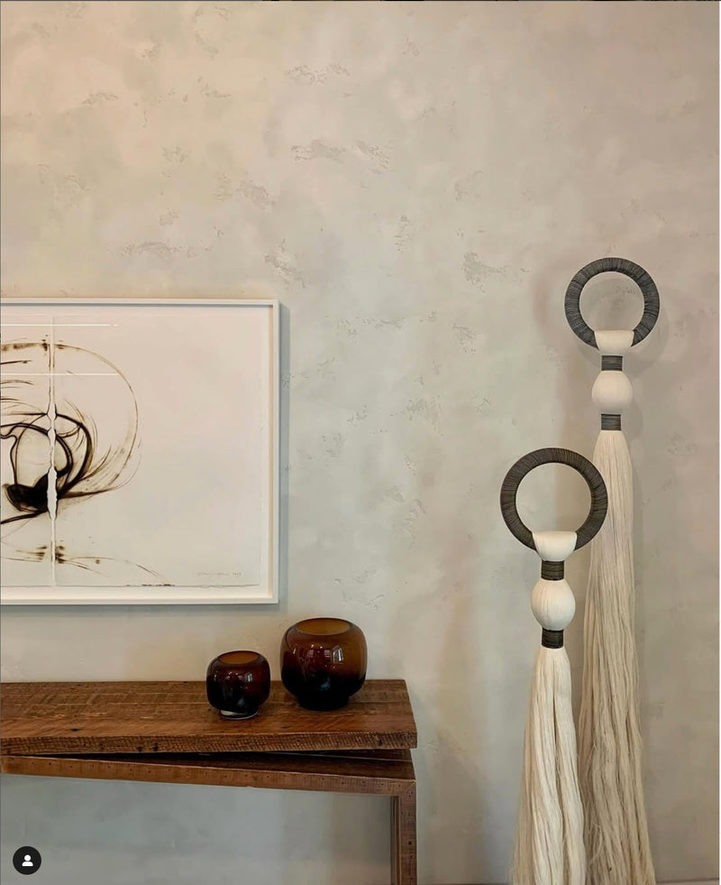 Neutral Intonachino Fine plaster wall with framed artwork, a wooden console and woven wall hangings