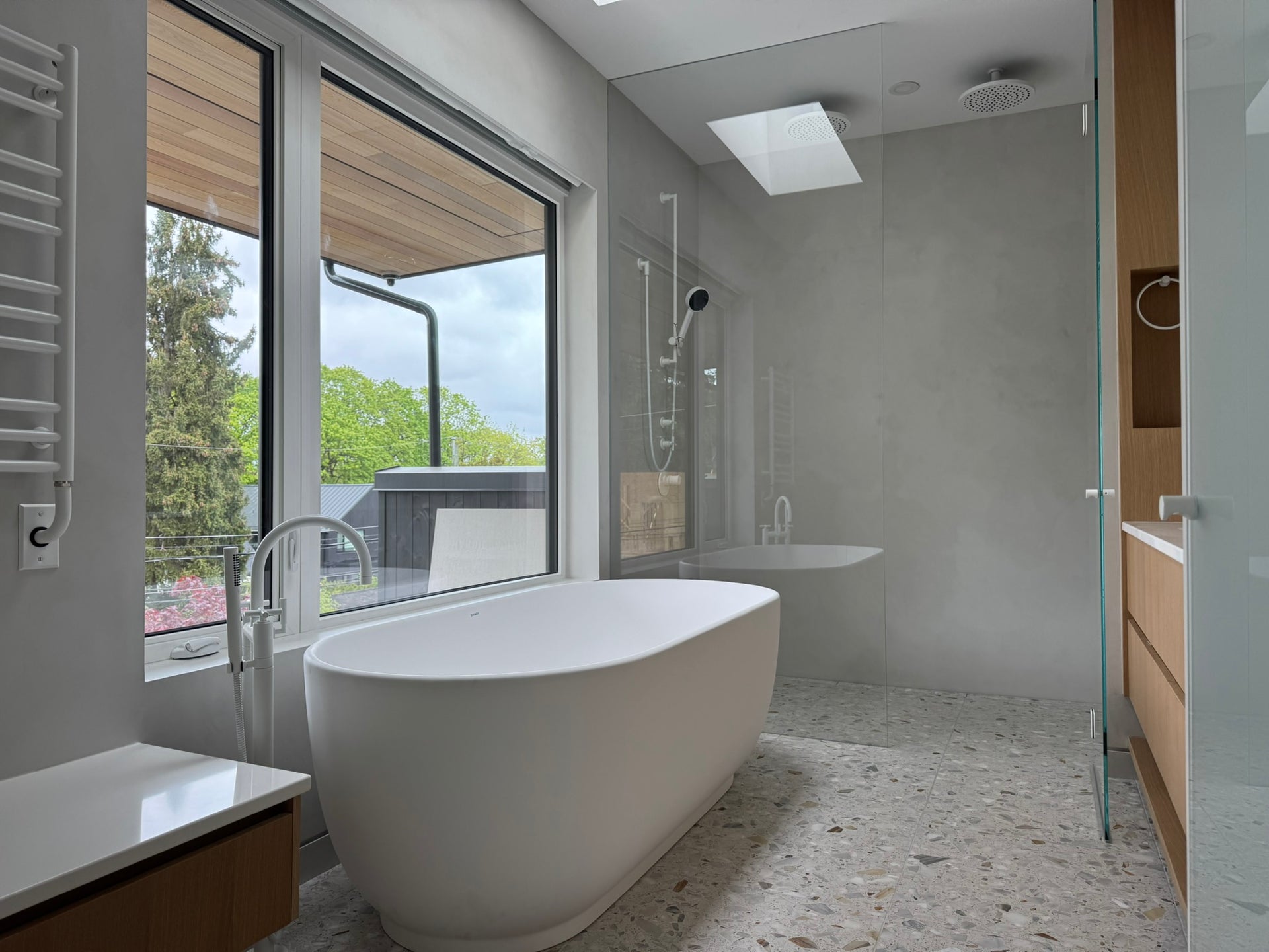 Cadoro Plus project with continuous shower walls, freestanding bath and wood cabinetry