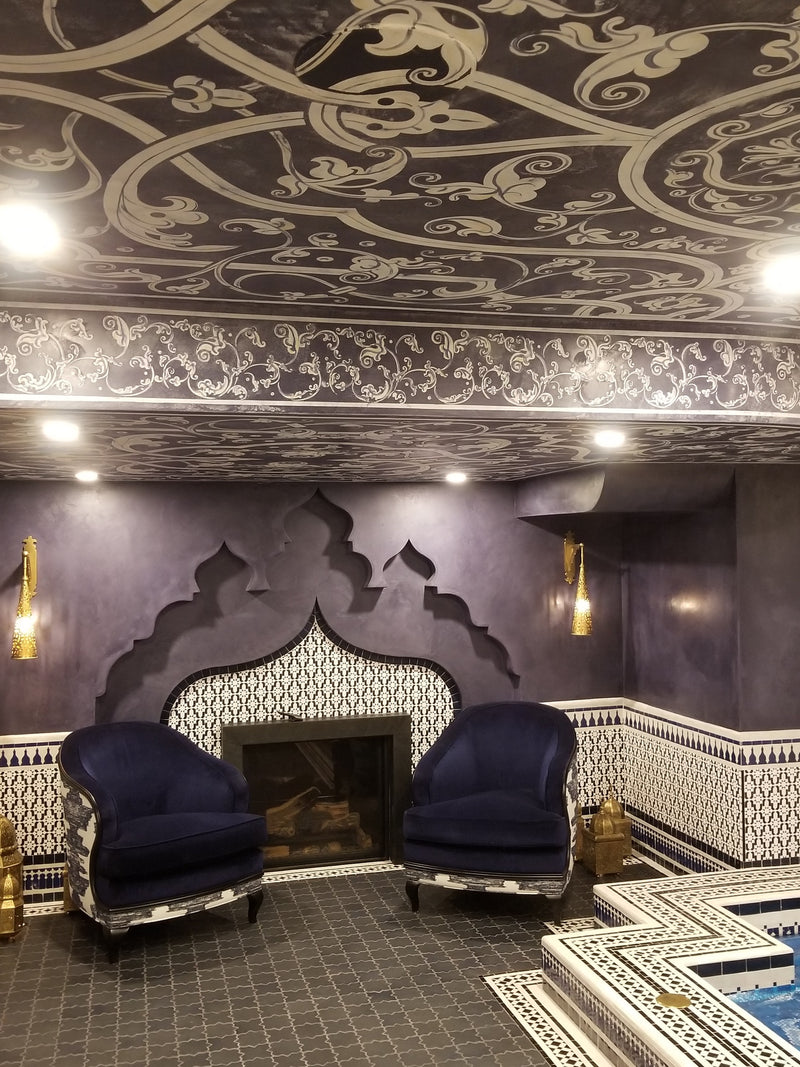 Tadelakt interior with plum plaster walls, decorative ceiling, tiled fireplace and blue chairs