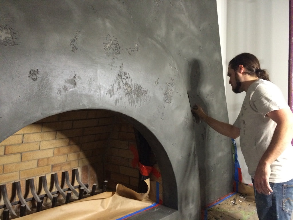 Applicator finishing grey Travertino plaster around a fireplace